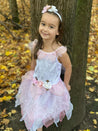 Girl leaning against a tree wearing the white and pink fairy dress.