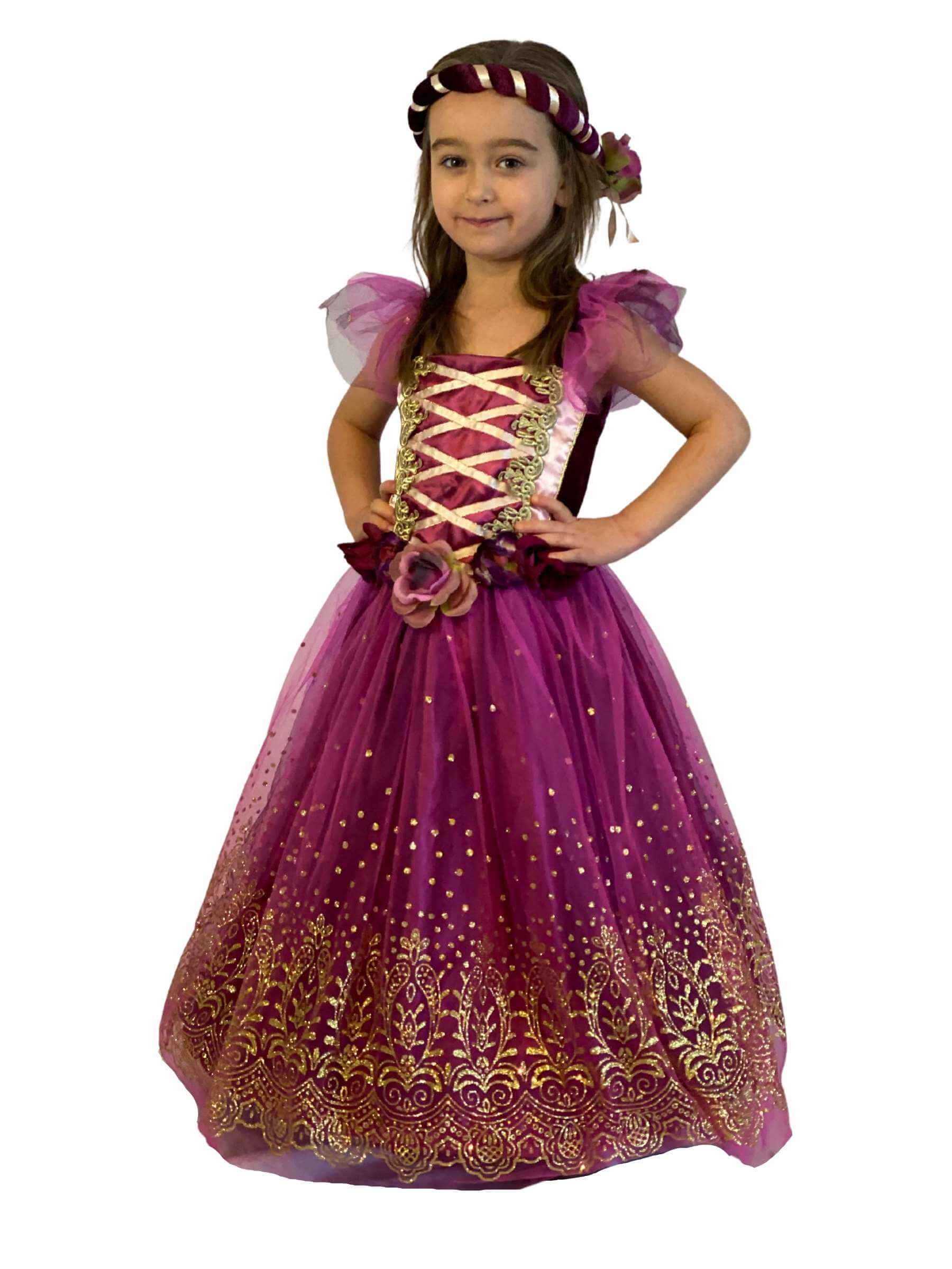 Girl wearing a plum coloured dress with gold details including gold glittered pattern to the skirt. The girl also wears a matching plum and gold headband.