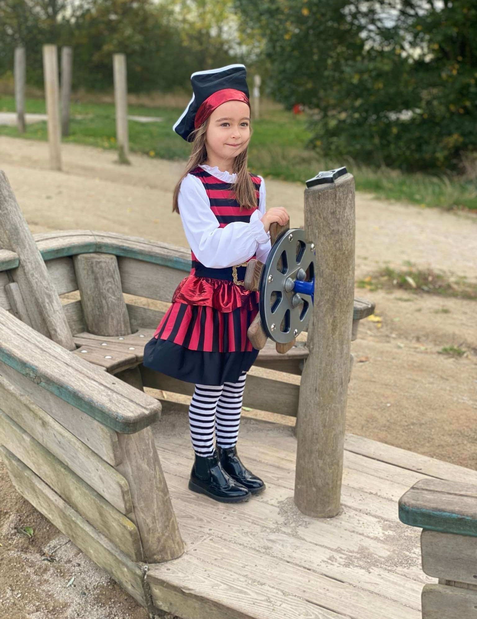A girl stood on a wooden boat wearing the pirate costume.