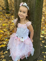 Girl leaning against a tree wearing the white and pink fairy dress.