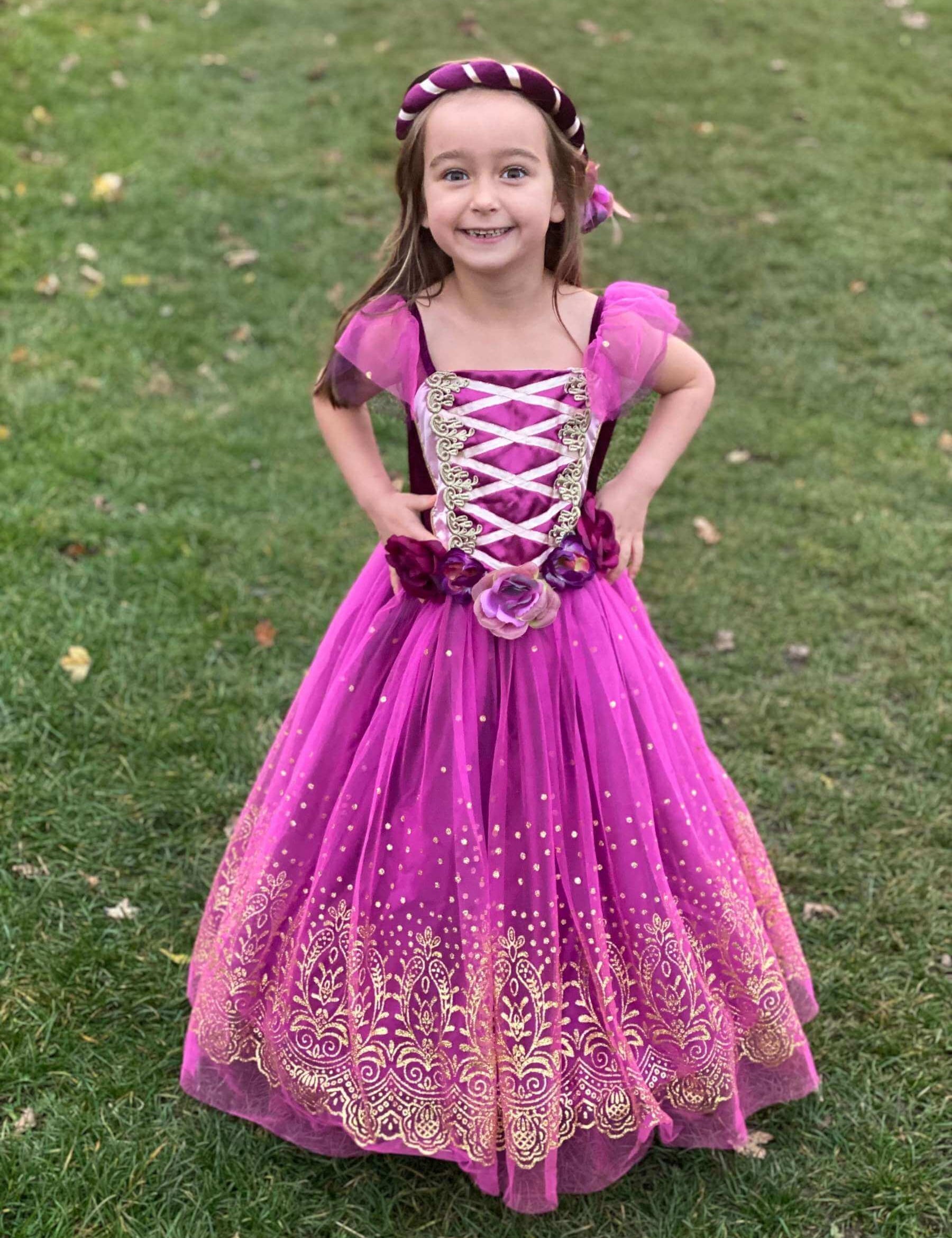 Girl stood on grass wearing the plum and gold princess dress.